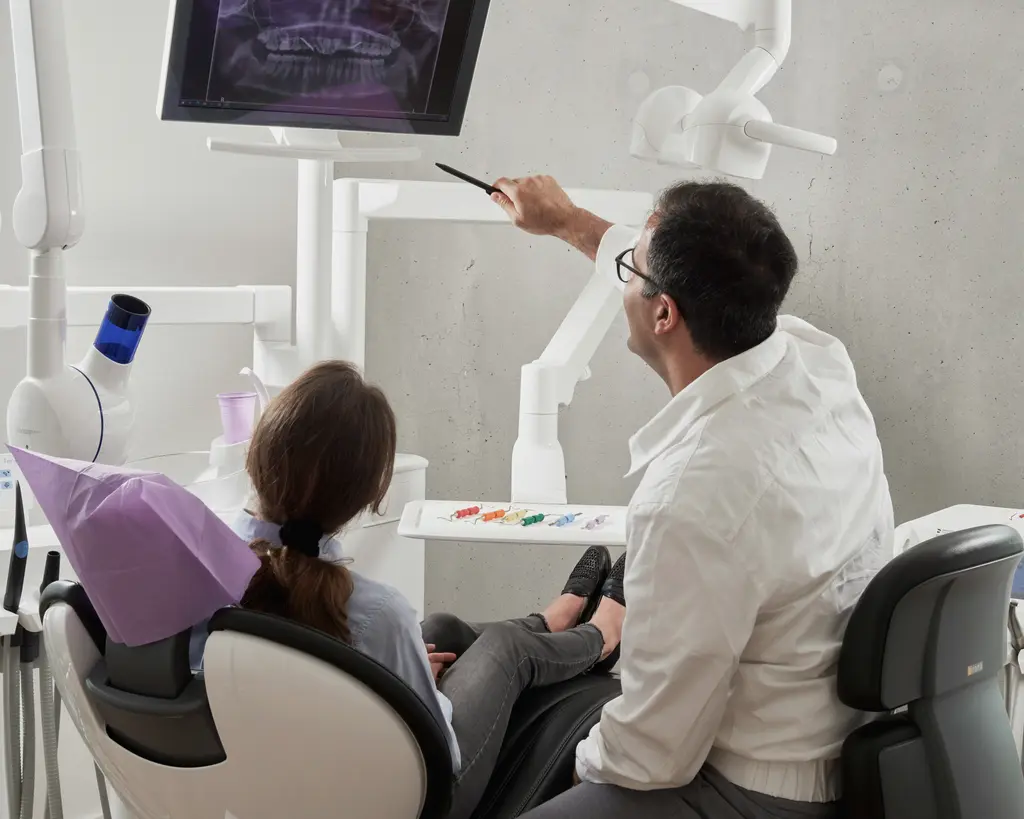 A dentist shows a patient her radiograph from the chair