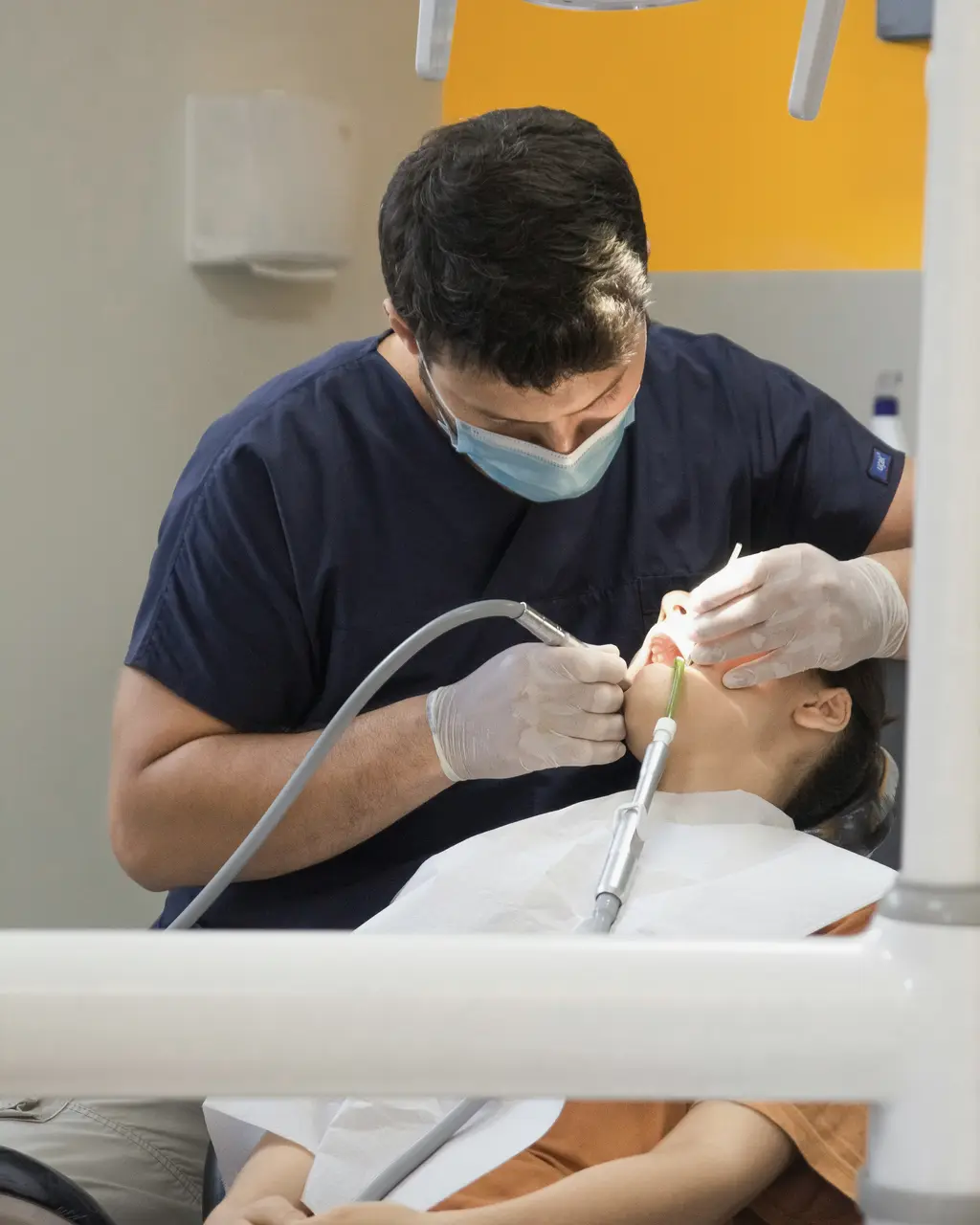 A dentist in navy scrubs treating a patient